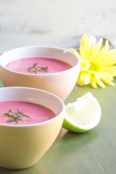 three bowls filled with soup and garnished with herbs next to a yellow flower