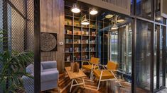 a room with chairs and tables inside of it next to a book shelf filled with books