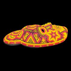 a yellow and red shoe with designs on the outstratche, in front of a black background