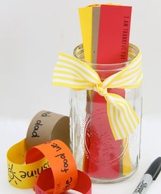 a jar filled with different colored paper and some scissors next to it on a table