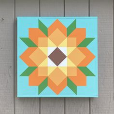 an orange and green flower is on a blue block with wood planks in the background