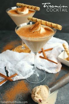 two martini glasses filled with cinnamon cocktail and topped with whipped cream on a gray surface