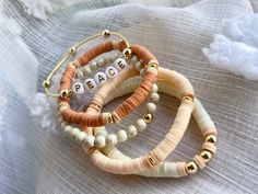 three bracelets with beads and words on them sitting on top of a white cloth