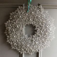 a snowflake wreath hanging on the front door with a green ribbon and bow