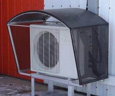 an air conditioner sitting on top of a metal stand next to a red building