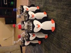 six plastic bottles with penguins painted on them sitting on the floor in front of a carpeted area