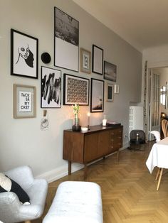 a living room filled with furniture and framed pictures on the wall above a dining table