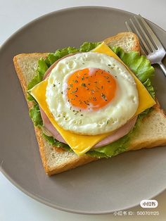 a sandwich with an egg and cheese on it sitting on a plate next to a fork