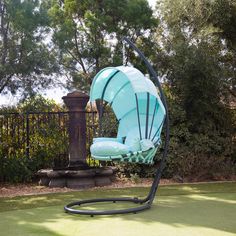 a swing chair in the middle of a lawn with trees and bushes behind it,