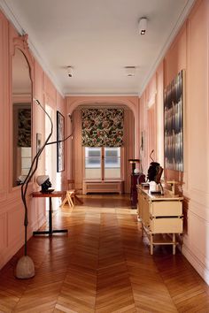 a long hallway with pink walls and wooden floors