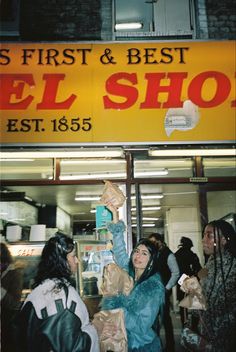 people are standing in front of an el shop with their hands up to the sign