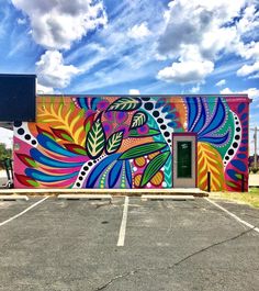 a colorful painted building with a green door in the parking lot and blue sky behind it