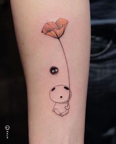 a small tattoo on the arm of a person with an orange flower in front of it