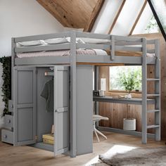 a loft bed with desk and ladders in a small room next to a window