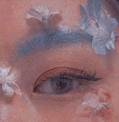 a woman's face with flowers in her hair and makeup on top of her eyes