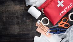 first aid supplies laid out on top of a wooden table, including scissors and bandages