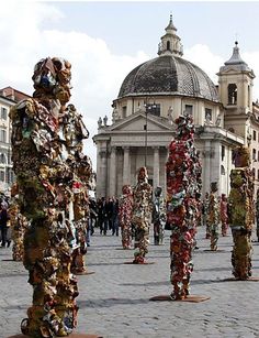 there are many sculptures in the middle of the street with people standing around them and buildings behind them