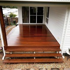 a wooden deck with two benches in front of it and a white house behind it