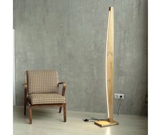 a wooden floor lamp sitting next to a chair in a room with concrete walls and wood floors