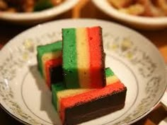 three pieces of cake on a plate with other plates and bowls in the back ground