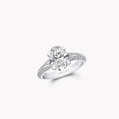 a diamond engagement ring with diamonds on the band and an oval shaped center stone in white gold