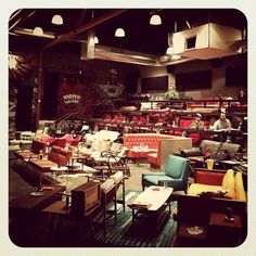 a large room filled with lots of furniture and lights hanging from the ceiling above it