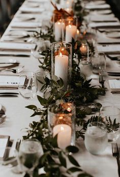 a long table with candles and greenery on it