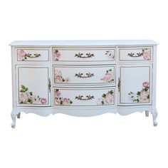 a white dresser with pink flowers painted on the side and gold trimming around it