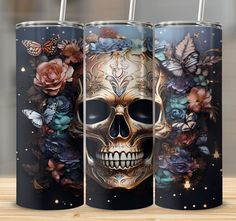 three stainless steel tumblers with skulls and flowers on them