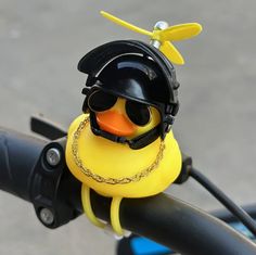 a rubber duck wearing a helmet and goggles on a bike handlebar with a chain around its neck