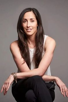 a woman sitting on the floor with her legs crossed and looking at the camera while smiling