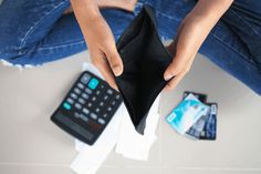 a person sitting on the floor with a wallet and remote control in front of them