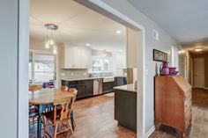 Kitchen remodel with white upper cabinets, a grey backsplash, light granite countertops, new vinyl plank flooring, and farm sink under the bay window