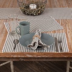 the table is set with two plates, silverware and a striped placemat on it