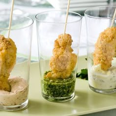 three shot glasses filled with different types of appetizers and dips on sticks