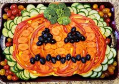 a platter filled with veggies and fruit in the shape of a pumpkin