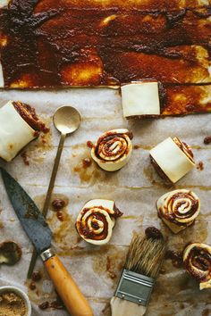 some food is laying out on a table with a spatula and brush next to it