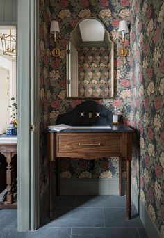 a bathroom sink sitting under a mirror next to a wall mounted vanity with flowers on it