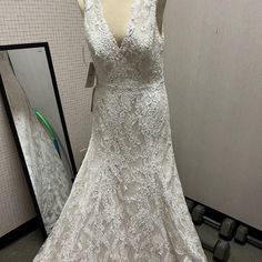 a white wedding dress on display in front of a mirror with the back cut out