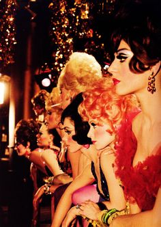 a group of women sitting next to each other in front of a christmas tree with lights