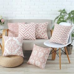 a couch with pink and white pillows sitting on top of it next to a chair