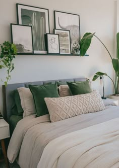 a bed with green pillows and pictures on the wall above it, in a bedroom