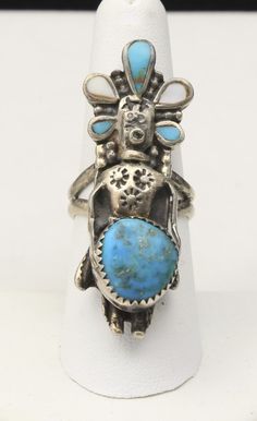 "-Vintage Hopi Kachina, sandcast silver, turquoise and mother of pearl (MOP) ring -Marked with a stylized J.B. and symbol on back of ring -Believed to be made by Johnny Blue Jay -Acid tested for Sterling silver -Great vintage condition, some tarnish on ring, ring has not been cleaned -Some natural inclusions in the turquoise -Turquoise: 12.53mm x 11.51mm irregular roundish, 8.73mm x 3.67mm pear, approx 2.40mm x 3.50mm pear (x2) -MOP: approx 5.31mm x 3.58mm pear (x2) -2\" tall x .75\" wide x .35\ Collectible Blue Multi-stone Turquoise Ring, Collectible Blue Turquoise Inlay Ring, Unique Turquoise Inlay Ring, Collectible Multi-stone Blue Turquoise Ring, Traditional Turquoise Rings Collectible, Vintage Turquoise Inlay Ring, Vintage Turquoise Ring With Inlay, Vintage Blue Rings With Inlay, Traditional Blue Turquoise Collectible Ring