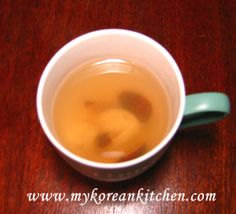 a white cup filled with liquid on top of a wooden table