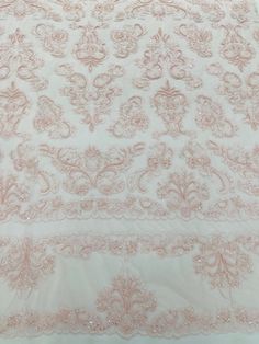 a white and pink table cloth with sequins on the edges, sitting on top of a bed