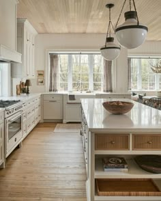 a large kitchen with white cabinets and wood flooring on the walls, along with an island in the middle