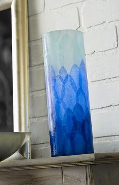 a blue vase sitting on top of a table next to a mirror