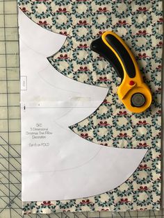 a pair of scissors sitting on top of a piece of paper next to a cut out christmas tree