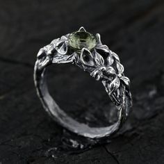 a close up view of a ring with leaves and flowers on the side, sitting on a black surface