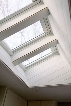 a kitchen with three skylights on the ceiling and cupboards in front of it